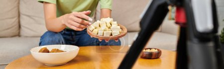 Photo for Cropped vegetarian woman showing tasty tofu cheese in front of digital camera, video blogger, banner - Royalty Free Image