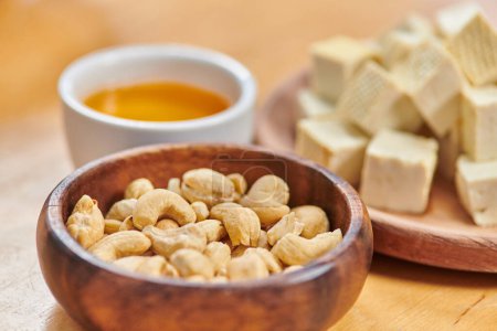 concept de régimes à base de plantes, gros plan sur les noix de cajou et les dés de tofu près de l'huile d'olive naturelle