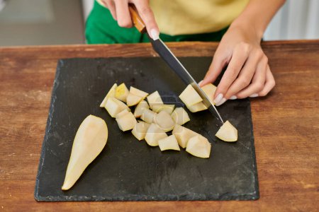 Photo for Cropped view of woman with knife cutting fresh ripe pear on chopping board, vegetarian culinary - Royalty Free Image