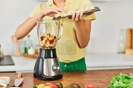 Photo for Cropped view of woman adding chopped fruits in electric blender, healthy vegetarian home cooking - Royalty Free Image