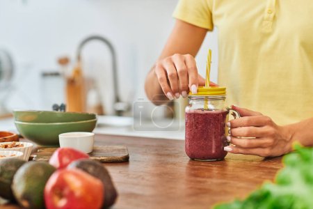 Photo for Cropped view of woman near mason jar with delicious plant-based smoothie near blurred fresh fruits - Royalty Free Image