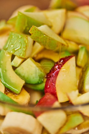 Nahaufnahme von köstlichem Obstsalat mit Äpfeln, Birnen und Avocado mit Honig, vegetarischer Hintergrund