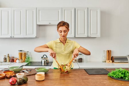 Vegetarierin mischt frischen Obstsalat in moderner Küche, gesundes und gesundes Ernährungskonzept
