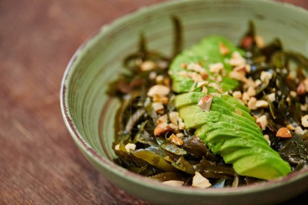 Photo for Close up view of vegetarian salad with seaweeds and sliced avocado with walnuts on wooden table - Royalty Free Image