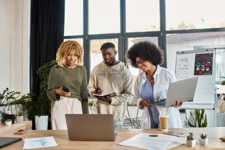alegre equipo de amigos afroamericanos trabajando juntos y mirando el ordenador portátil, concepto de negocio