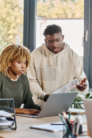 Foto de Amigos afroamericanos enfocados trabajando en su proyecto y mirando a la computadora portátil, proyecto de negocios - Imagen libre de derechos