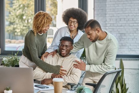 gut aussehende afrikanisch-amerikanische Freunde in lässiger Kleidung lachen zusammen im Büro, Coworking