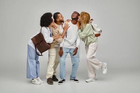cheerful caring group of friends hugging and laughing together on gray backdrop, studying concept