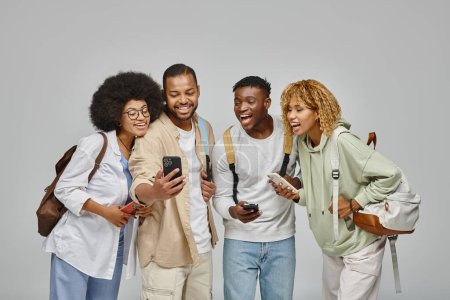 joven hombre guapo mostrando a sus amigos algo alegre en su teléfono, estilo de vida estudiantil