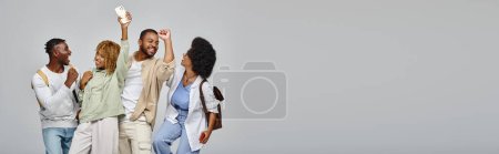 young students cheering and smiling joyfully posing on gray background, studying concept, banner