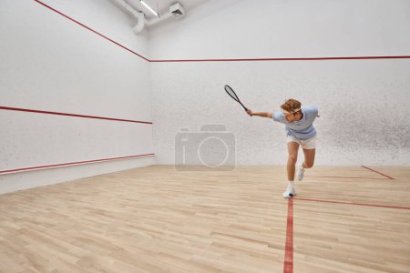 Photo for Young and active redhead man in sportswear playing squash inside of court, challenge and motivation - Royalty Free Image