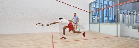 dynamic multicultural sportsmen playing squash together inside of court, sport and motivation banner