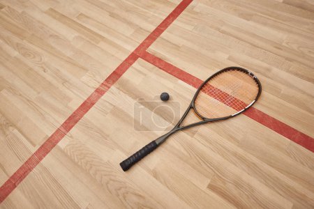 pelota de squash y raqueta en el suelo dentro de la cancha cubierta, la motivación y el concepto de determinación