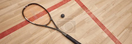 piłka do squasha i rakieta na podłodze wewnątrz krytego boiska, baner motywacyjny i determinacyjny