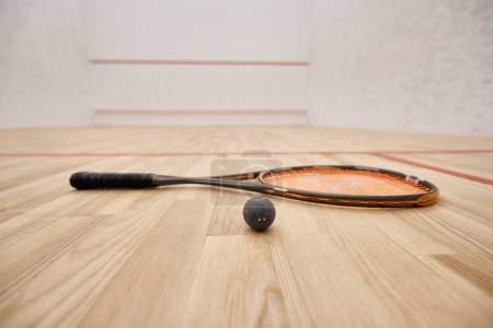 ball and racquet on floor inside of indoor squash court, motivation and determination concept