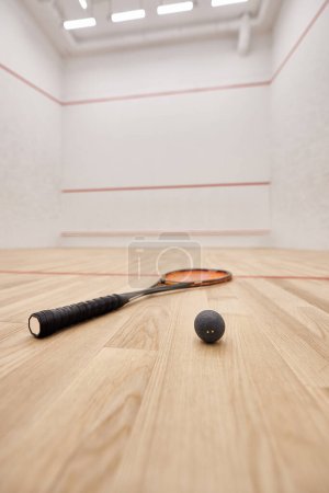 squash ball y raqueta dentro de la cancha con paredes blancas, motivación y concepto de determinación