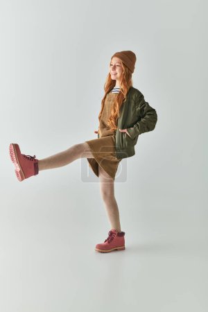 Photo for Child fashion, joyful girl with long hair and winter hat on head standing in dress and jacket - Royalty Free Image