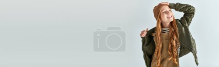 Téléchargez les photos : Heureux preteen fille en bonnet tricoté et vêtements chauds ajustement veste d'hiver sur gris, bannière - en image libre de droit