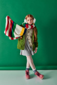 preteen kid in ear muffs and scarf standing in winter outfit on turquoise backdrop, pouting lips tote bag #680989264