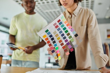 Ausgeschnittene Ansicht einer Frau mit Farbpalette in der Nähe eines amerikanischen Designers im Druckstudio