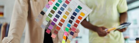 Téléchargez les photos : Foyer sélectif des échantillons de couleur près des concepteurs interracial cultivés en studio d'impression, bannière - en image libre de droit