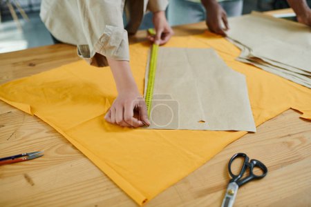 Photo for Cropped view of creative multicultural fashion designers measuring sewing patterns in print studio - Royalty Free Image