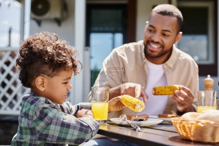 positivo africano americano niño tener familia barbacoa con padre en patio trasero de la casa, zumo de naranja
