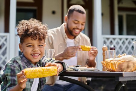 alegre africano americano niño tener familia barbacoa con padre en patio trasero de la casa, jugo de naranja