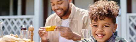 cheerful african american kid having family bbq with father on backyard of house, banner