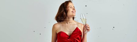 New Year banner, cheerful woman in party attire holding glass of champagne near confetti on grey