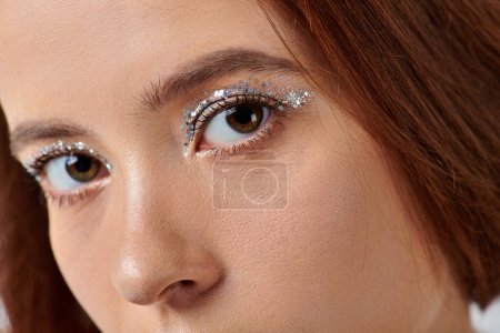 close up portrait of woman with holiday makeup looking at camera, shiny silver eye shadow