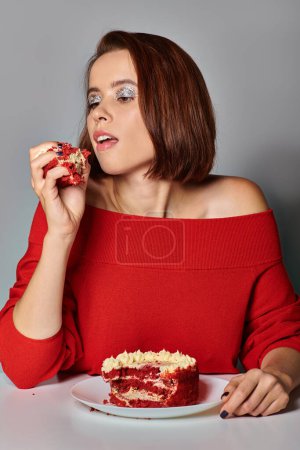 schöne Frau in roter Kleidung mit einem Stück Bento-Kuchen auf grauem Hintergrund, Happy Birthday