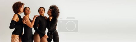 Téléchargez les photos : Quatre femmes afro-américaines attrayantes en costume séduisant noir posant ensemble, mode, bannière - en image libre de droit
