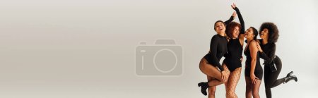 Photo for Young joyful african american women in black sexy outfits posing happily in motion, fashion, banner - Royalty Free Image