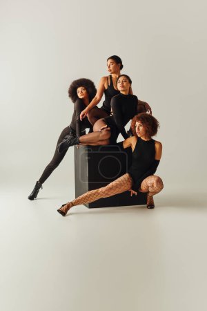 Photo for Appealing african american women in sexy bodysuits posing together on black cube, fashion concept - Royalty Free Image