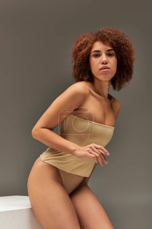 beautiful young african american woman in pastel underwear with hands near face, fashion concept