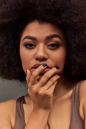 mujer afroamericana joven en ropa interior pastel con esmalte de uñas negro posando seductoramente, moda