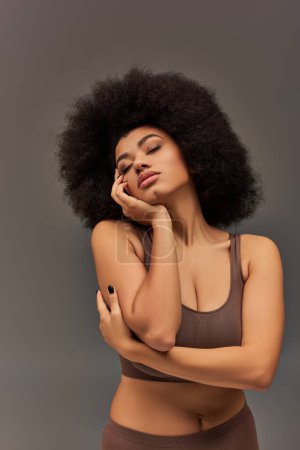 junge Afroamerikanerin in pastellfarbener Unterwäsche mit schwarzem Nagellack posiert verführerisch, Mode
