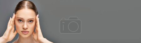 Téléchargez les photos : Portrait de jeune femme avec une peau parfaite posant avec les mains près du visage sur fond gris, bannière - en image libre de droit