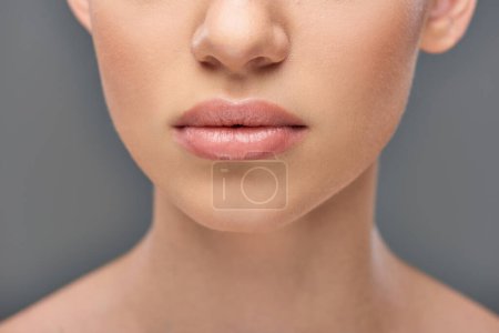 close up of young woman with juicy lips and perfect skin posing on grey background, youth and beauty