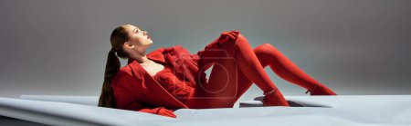 Téléchargez les photos : Bannière de jolie jeune femme en tenue rouge avec gants et blazer posant sur fond gris - en image libre de droit