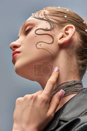Nahaufnahme des schönen jungen Modells mit trendigen Perlstiften im Haar und roten Lippen vor grauem Hintergrund