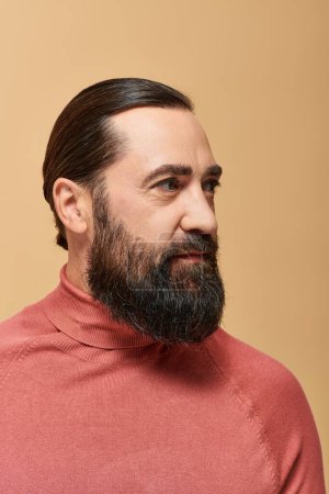 portrait of handsome man with beard posing in pink turtleneck jumper on beige background, serious Poster 684012794