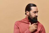 portrait of handsome man with beard posing in turtleneck jumper on beige background, serious t-shirt #684013266