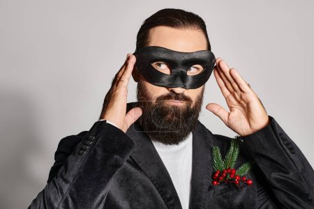 Masquerade, handsome bearded man in carnival mask and elegant formal wear on grey backdrop