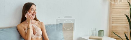 Photo for Alluring joyful woman in beige lingerie with long hair talking by phone and smiling happily - Royalty Free Image