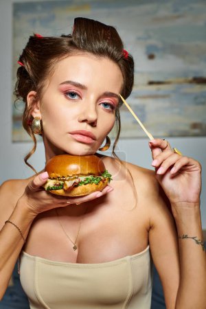 beautiful appealing woman in beige sexy corset holding huge delicious burger and looking at camera