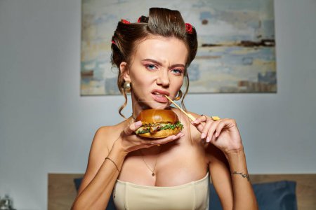 young emotional woman in beige sexy corset holding huge delicious burger and looking at camera