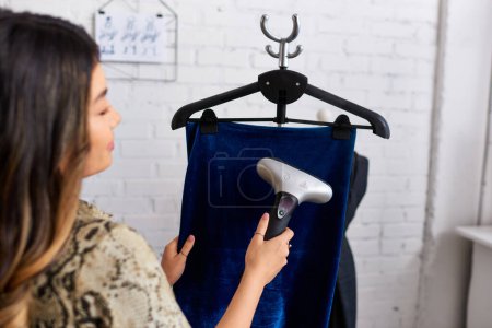 verschwommen asiatischen Stylisten dampfenden Qualität Velours Stoff in modernen Mode-Atelier, erfolgreiches Geschäft
