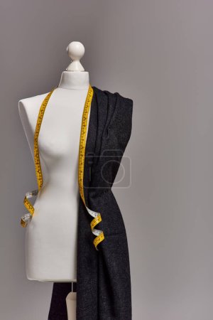 mannequin avec tissu de qualité et ruban à mesurer sur fond gris, concept d'entreprise de mode